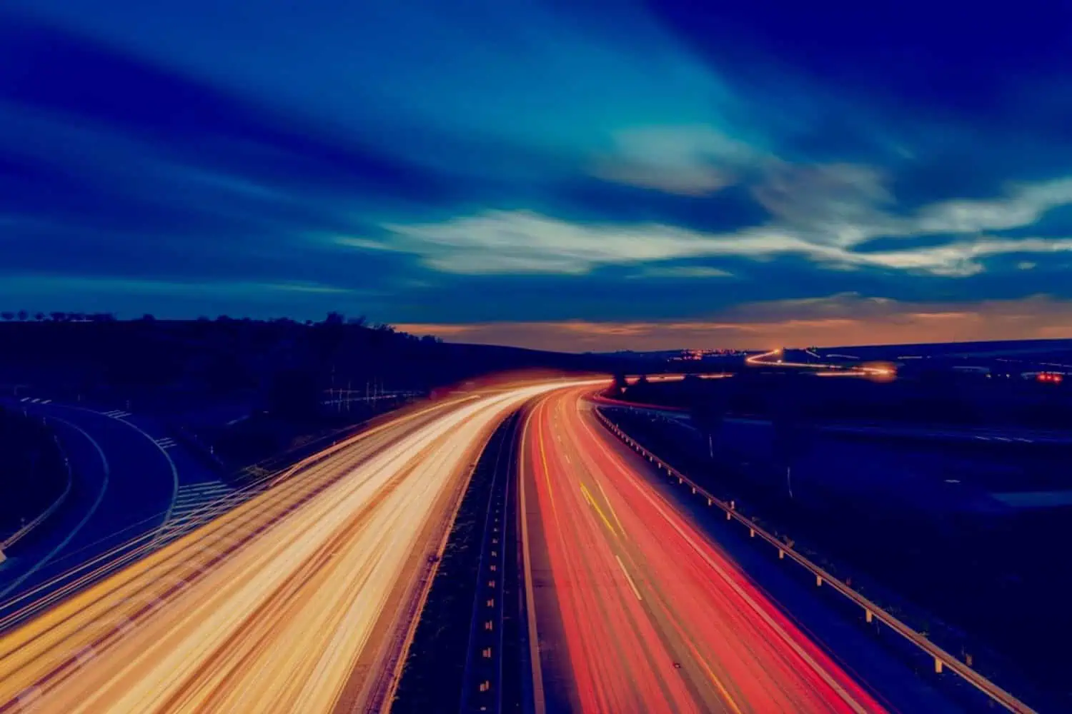 A multi-lane highway filled with streaks of vehicle lights at night