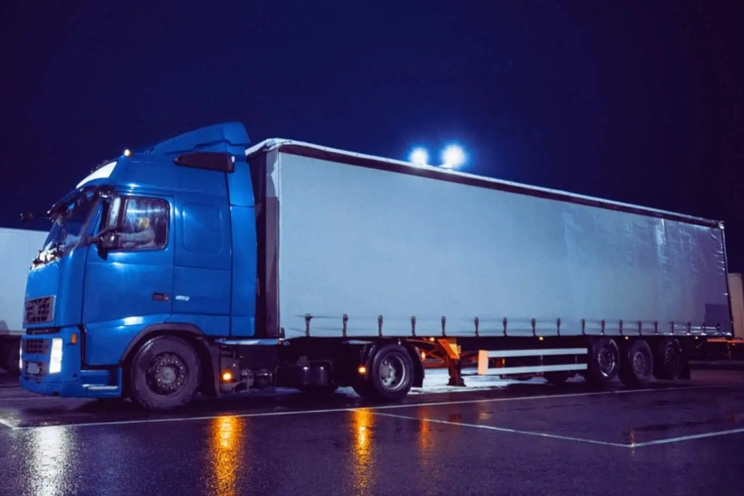 A freight semi-truck preparing to park at a shipping facility dock