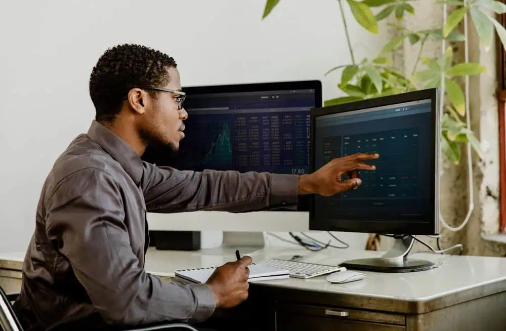 A man reviewing digital analytics from two computer monitors