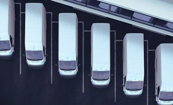 Limited parking lot with white delivery vans, showcasing logistics and fleet management solutions from Banyan Technology.