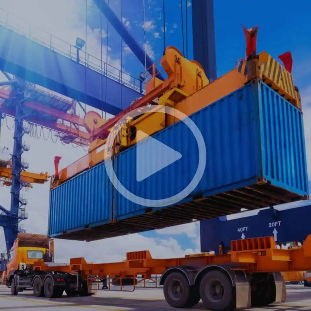 Loading container onto transport truck with heavy machinery at port or shipping yard for logistics and freight management.