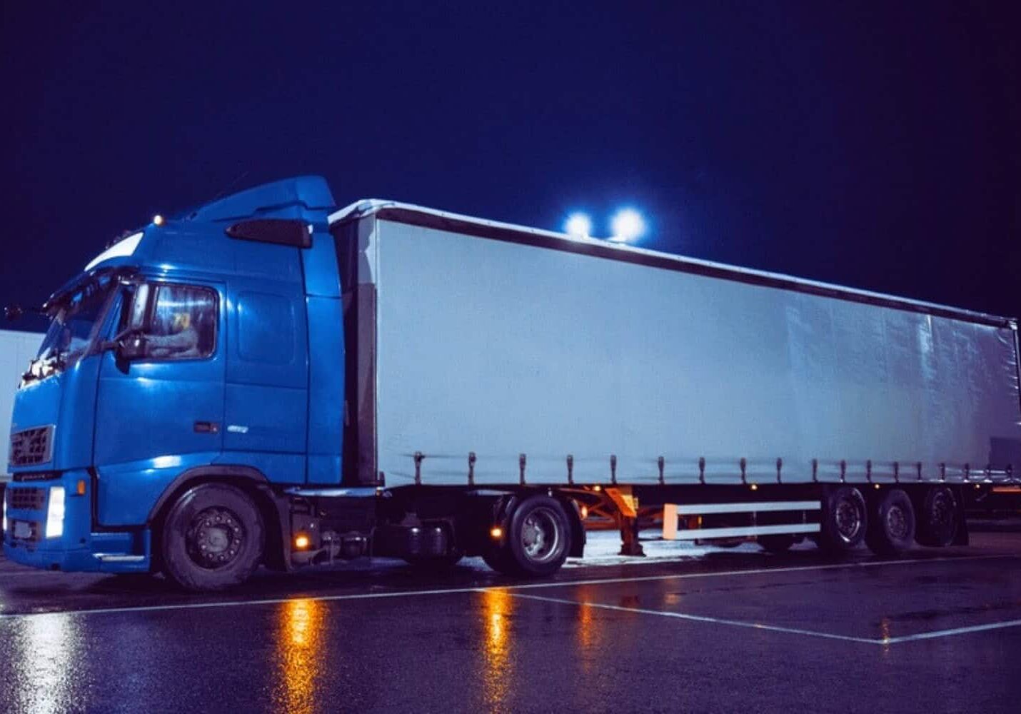 A freight semi-truck preparing to park at a shipping facility dock